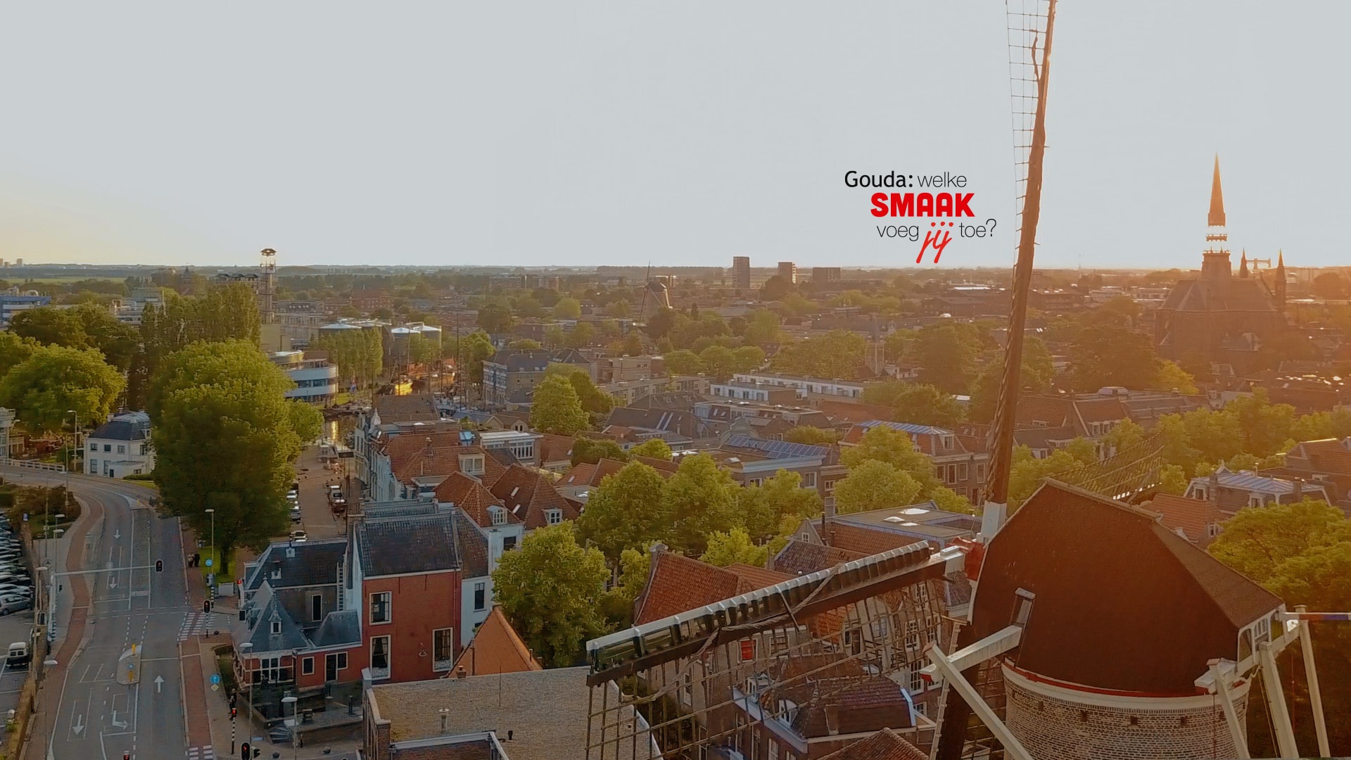 Luchtfoto van Gouda met op de voorgrond een molen. Rechts van het midden het logo Gouda: welke smaak voeg jij toe?